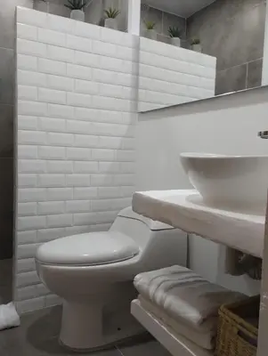 a white bathroom with a toilet and a sink at La Casa de Nelly - Medellín in Medellín