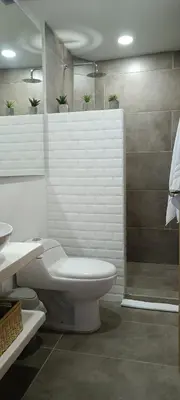 a white bathroom with a toilet and a shower at La Casa de Nelly - Medellín in Medellín