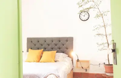 a bedroom with a bed with yellow pillows and a clock at La Liebre bed and breakfast in El Retiro