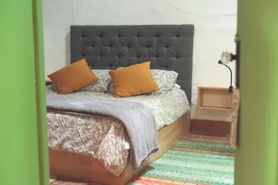 a bedroom with a bed with a black headboard and orange pillows at La Liebre bed and breakfast in El Retiro