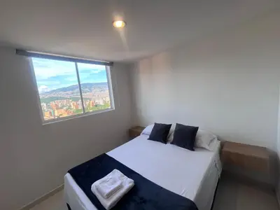 a bedroom with a bed and a large window at Hermoso y confort Apto en Medellín Cerca al Metro in Medellín