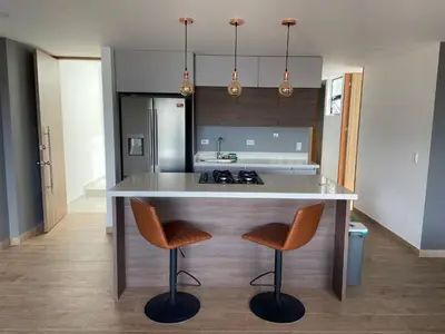 a kitchen with a counter and two stools in a kitchen at Balcones de la pradera by Hope in Guatapé