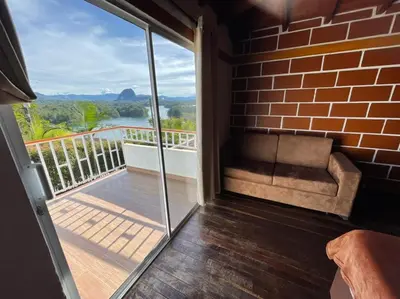 a room with a balcony with a couch and a window at Finca-hotel Montecarlo Guatape by Hope in Guatapé