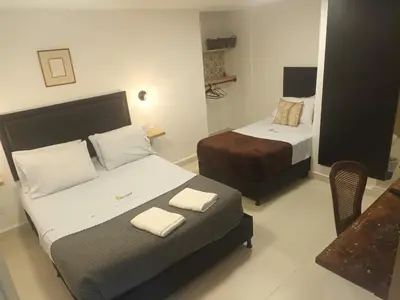 a hotel room with two beds and a chair at Casa Los Naranjos Hostal in Medellín