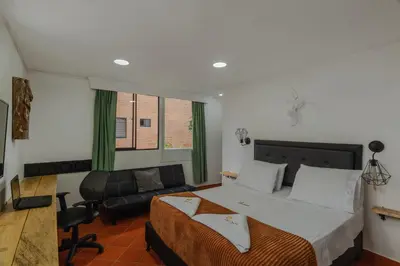 a bedroom with a large bed and a chair at Casa Los Naranjos Hostal in Medellín