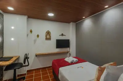 a bedroom with a bed and a tv on a wall at Casa Los Naranjos Hostal in Medellín