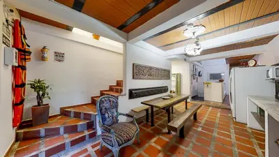a living room with a table and a refrigerator at Casa Los Naranjos Hostal in Medellín