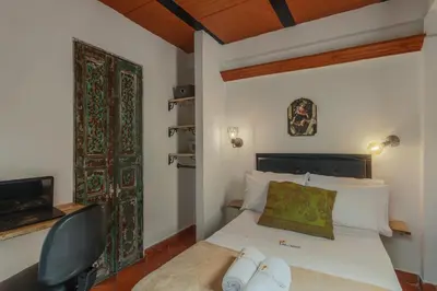 a small bedroom with a bed and a chair at Casa Los Naranjos Hostal in Medellín