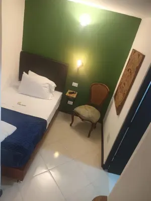 a small room with a bed and a chair at Casa Los Naranjos Hostal in Medellín