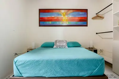 a bedroom with a blue bed with a painting on the wall at Rústic-HOUSE Envigado in Envigado