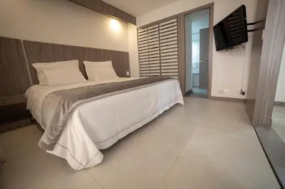 a bedroom with a large bed and a flat screen tv at Hotel Torre Poblado in Medellín