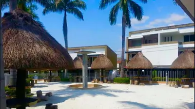 a beach with some straw umbrellas and palm trees at CASA VACACIONAL CON PISCINAS EN SAN JERONIMO - CIUDADELA PREMIUm in Medellín