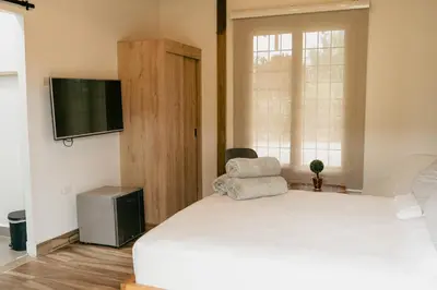 a bedroom with a white bed and a television at Finca hotel la fortuna in San Pedro