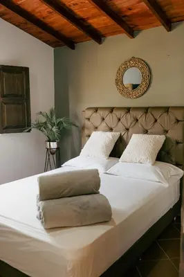 a bedroom with a large bed with white sheets and a mirror at Finca hotel la fortuna in San Pedro