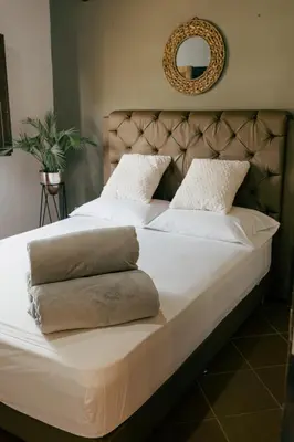 a large bed with white sheets and pillows on it at Finca hotel la fortuna in San Pedro