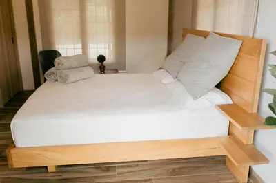 a bed with white sheets and pillows on it at Finca hotel la fortuna in San Pedro