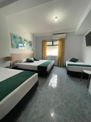 a hotel room with two beds and a window at Hotel Primavera Santa Fe in Santa Fe de Antioquia