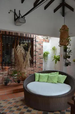 a wicker couch with green pillows in a room at Hotel Primavera Santa Fe in Santa Fe de Antioquia