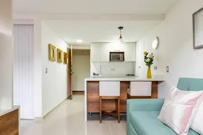a living room with a blue couch and a kitchen at Fabulous studio in the heart of Medellín in Medellín