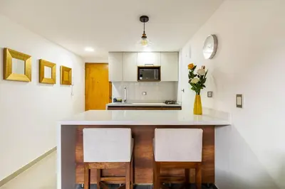 a kitchen with a white counter and two chairs at Fabulous studio in the heart of Medellín in Medellín