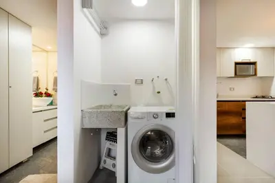 a white kitchen with a washing machine and a sink at Fabulous studio in the heart of Medellín in Medellín