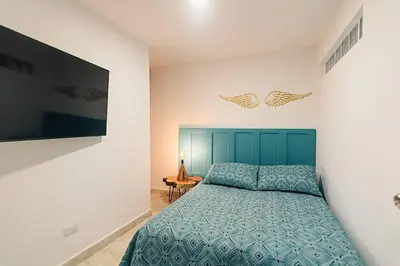 a bedroom with a blue bed and a flat screen tv at Hermoso y cómodo apartamento en El Poblado!!! in Medellín