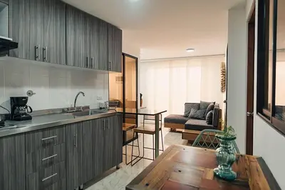a kitchen and living room with a table and a couch at Hermoso y cómodo apartamento en El Poblado!!! in Medellín