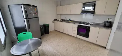 a kitchen with a green chair and a refrigerator at 1023 Los Colores Estadio apartamento - Parqueadero - Zona Wifi - Coworking - Área exclusiva de la ciudad in Medellín