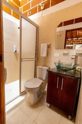 a bathroom with a toilet and a glass sink at Finca-Hotel Montecarlo Guatape by Hope in Guatapé