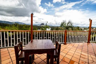 a wooden table and chairs on a deck with a fence at Finca-Hotel Montecarlo Guatape by Hope in Guatapé