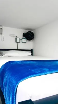 a bedroom with a bed with a blue blanket on it at Kromatic Hostel in Medellín