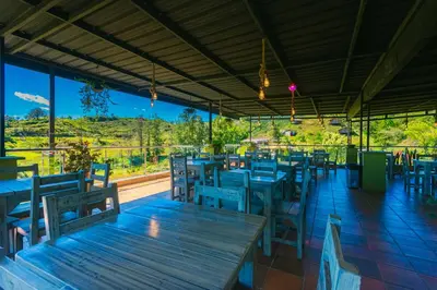 a restaurant with wooden tables and chairs with a view at Hotel Bambu Guatape in Guatapé