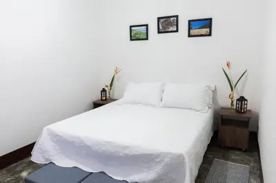 a bedroom with a white bed and two tables at Encanto! Casa de campo en Café de la Cima in Fredonia