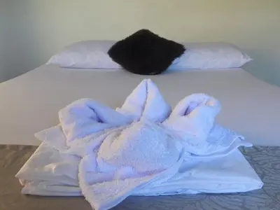 a white bed with a pile of towels on it at Hotel SG in Doradal