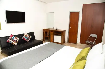 a bedroom with a bed and a couch and a television at Ayenda 1133 Casa Polty in Manizales