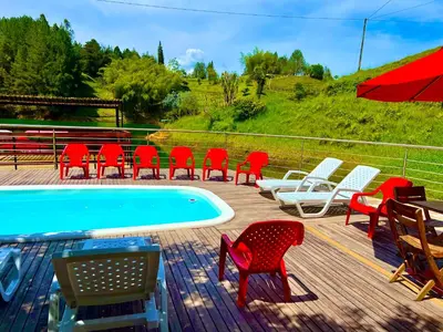 a deck with red chairs and a swimming pool at Finca Santa Monica Guatape in Guatapé