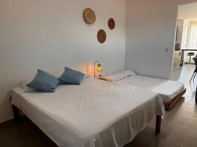 two beds in a room with white walls and blue pillows at Lagom Apartamentos San Rafael in San Rafael