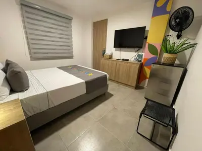 a bedroom with a bed and a tv and a chair at Hotel Medallo City in Medellín