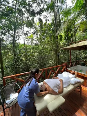 a woman standing on a deck with a man laying on a bed at ECO HOTEL RIO DE ORO in San Rafael