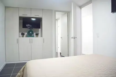 a white bedroom with a bed and a tv at Espectacular apt 3 habitaciones deluxe! in Envigado
