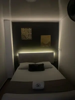 a small bedroom with a bed with a black headboard at Hotel Pass, Laureles Medellín in Medellín