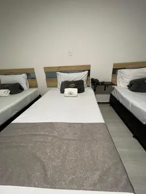 a bedroom with two beds with a bag on it at Hotel Pass, Laureles Medellín in Medellín