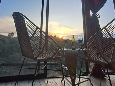 two chairs and a table with wine glasses on a balcony at Chalet de Liz - Guatapé in Guatapé