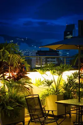 a patio with tables and chairs at night at Hotel California City in Medellín