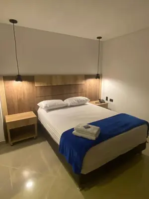 a bedroom with a large bed with a blue blanket at Hotel California City in Medellín