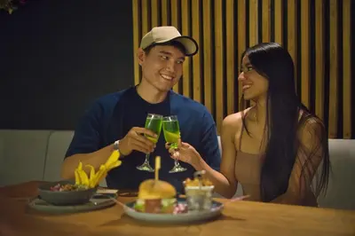 a man and a woman sitting at a table with drinks at Hotel California City in Medellín
