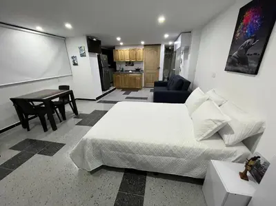 a bedroom with a bed and a table and a kitchen at Puesta de Sol El Carmen de Viboral in Carmen de Viboral