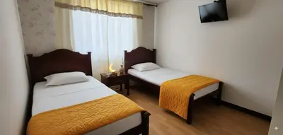 a hotel room with two beds and a television at Fuera de Casa como en Casa in Manizales