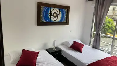 a room with two beds and a window with a picture at Amoblado laureles San Joaquín in Medellín