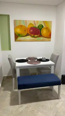 a table with a blue bench and a painting of fruit at Amoblado laureles San Joaquín in Medellín